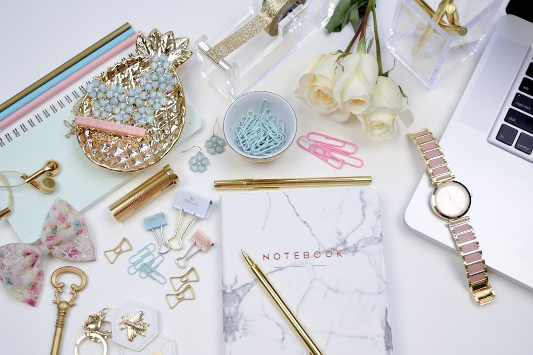Flatlay of designer sunglasses, perfume bottle and jewelry on a pastel surface